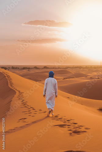 Anonymous Berber person walking on sand in desert photo