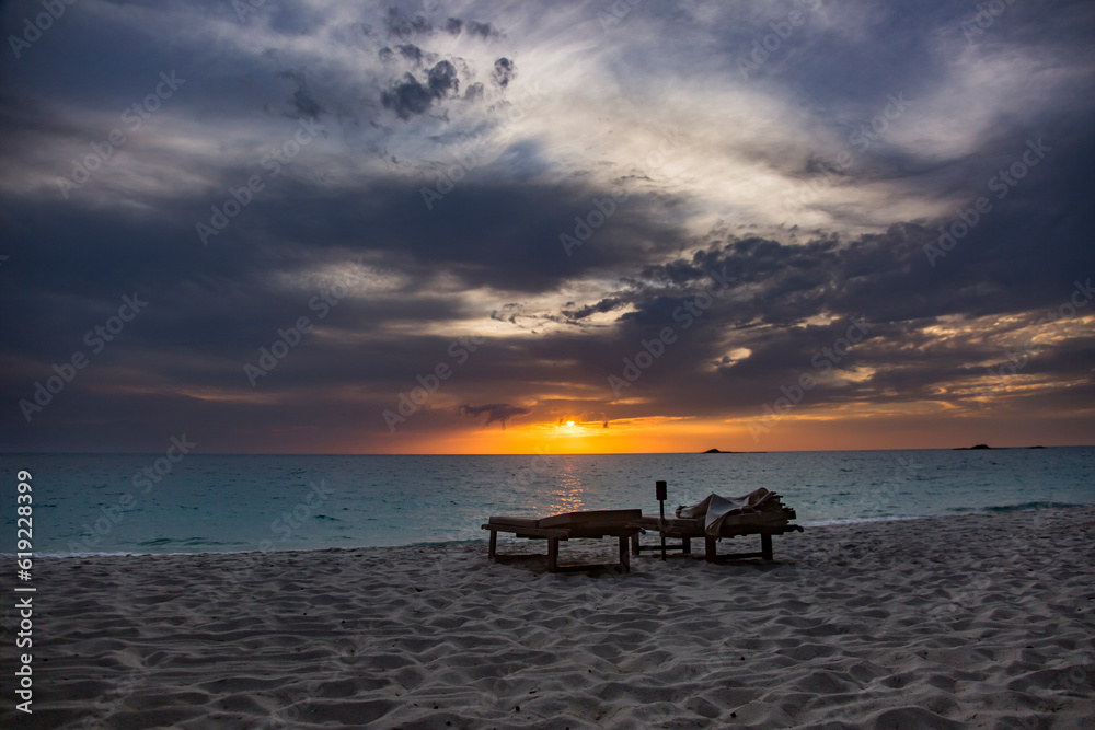 Empty deck chairs near calm sea at beach during sunset Empty deck chairs near calm sea at beach during sunset