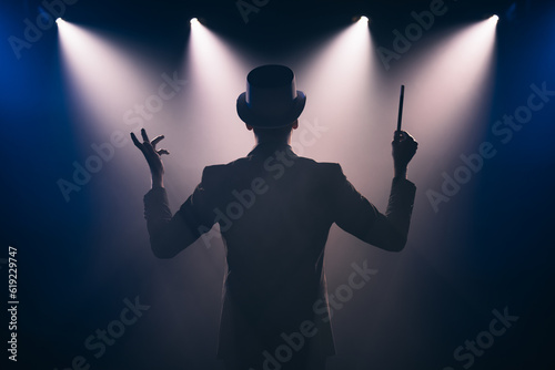 Man with magic wand on stage in spotlight