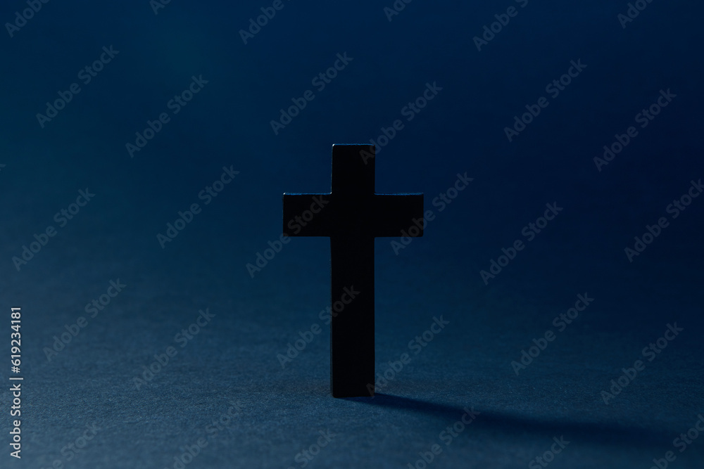 Mysterious classic dark cross isolated on the dark solid fond blue background