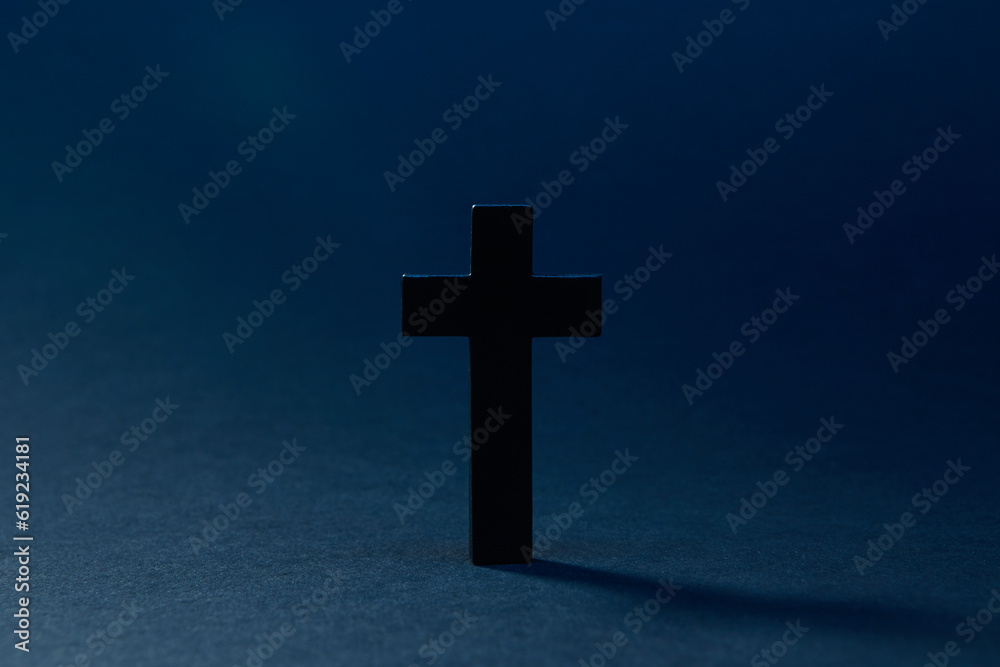 Mysterious classic dark cross isolated on the dark solid fond blue background