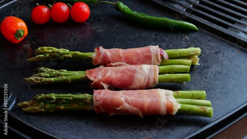 fried, cooking on grill green asparagus wrapped in jamon