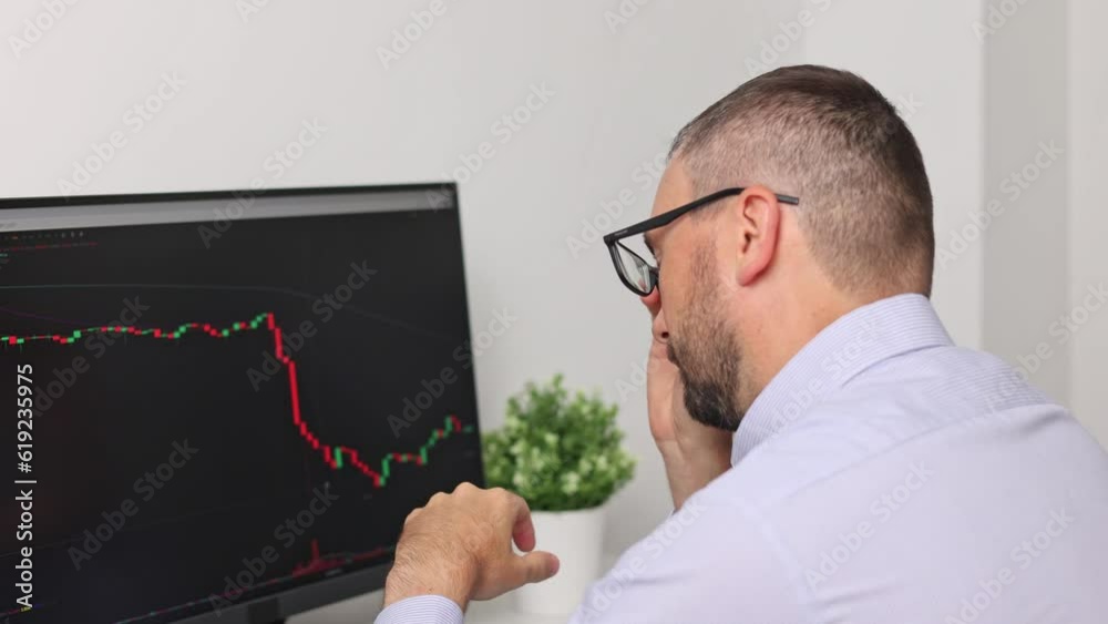 A frustrated or tired stock trader looks at the value is falling on the monitor screen. Bitcoins, futures, investment market. Bitcoins, futures, investment market. A frustrated or tired stock trader looks at the value is falling on the monitor screen. Bitcoins, futures, investment market. Bitcoins, futures, investment market.