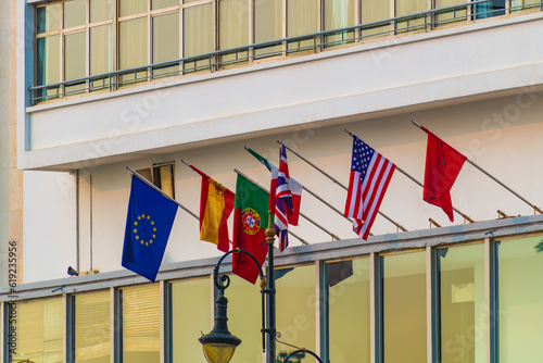 Fotografía National flags of the European Union, Spain, Portugal, France, the United States and the Kingdom of Morocco, mounted on a flagpole on a street in the city of Tangier, Morocco