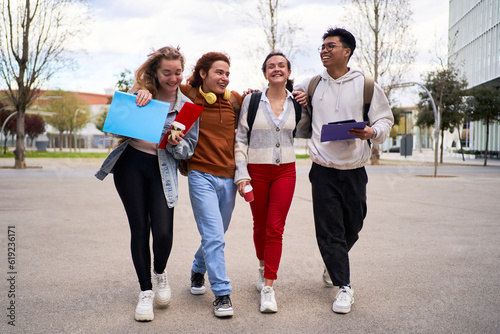 Group of university young students walking together in a high school campus  embracing each other and laughing after class.