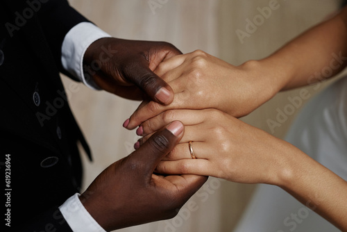 Closeup of black young couple getting married with bride and groom holding hands, focus on wedding rings
