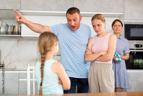 Family scene in kitchen, unpleasant conversation Parents stand face to face with daughter and scold for disobedience, unreasonable behavior