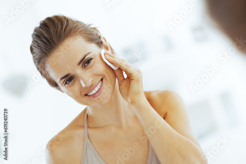 happy young woman using cotton pad in bathroom