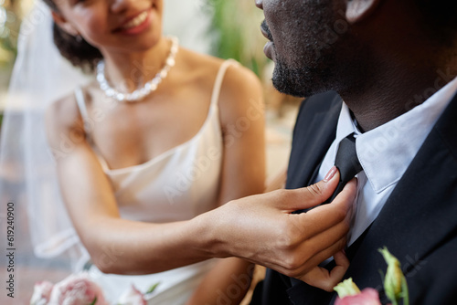 Closeup of black couple getting married with bride adjusting tie for groom, copy space
