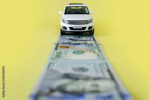 White toy car on money road on yellow background