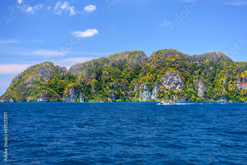Motor ship in the bay of Ko Phi Phi Don Island with huge rocks and cliffs on a sunny day, Ao Nang, Mueang Krabi District, Krabi, Andaman Sea, Thailand