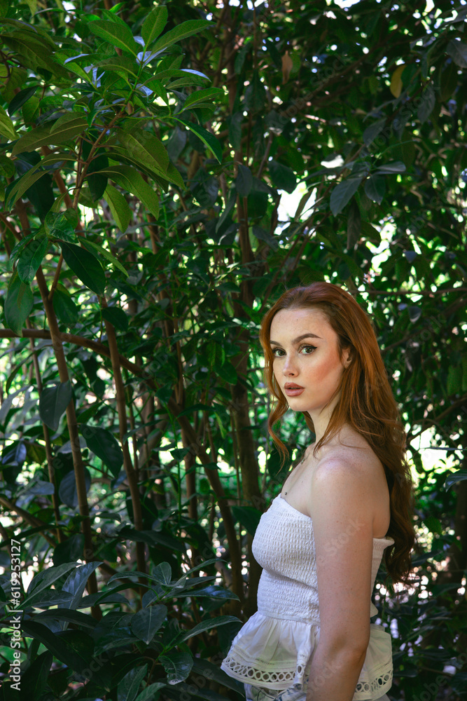 very beautiful freckled white woman with long red hair in a garden of green leaves very beautiful freckled white woman with long red hair in a garden of green leaves