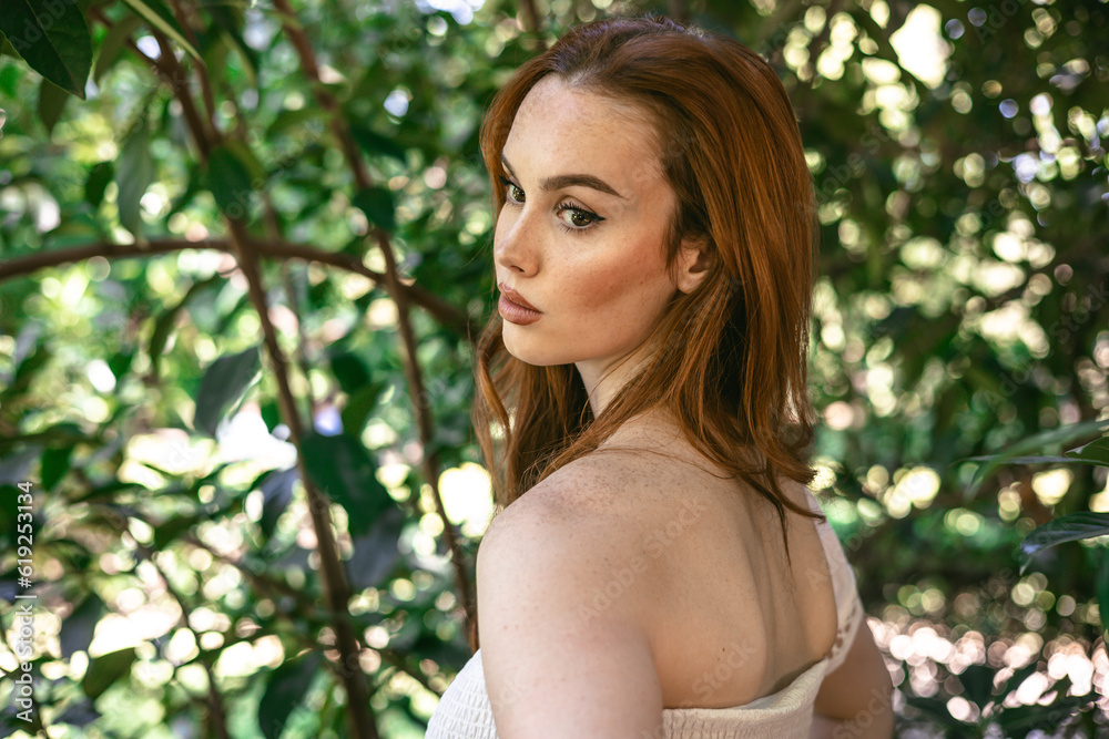 very beautiful freckled white woman with long red hair in a garden of green leaves very beautiful freckled white woman with long red hair in a garden of green leaves