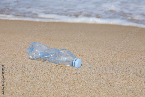 Used plastic bottle on sand near water. Recycling problem