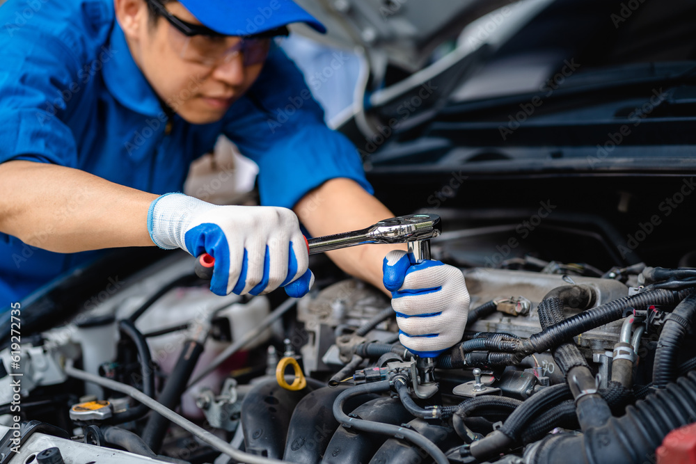 Obraz premium Close up of view Auto mechanic repairman using a socket wrench working engine repair in the garage, changing spare parts, checking the mileage of the car, checking and maintenance service concept.
