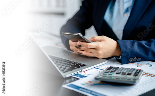 Close up view of Businesswomen or Accountants using smartphones while working analyzing business report graphs and finance charts at the workplace, financial and investment concept.