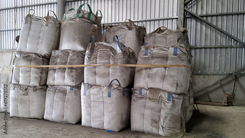 A large number of large bigbag poly sacks of industrail waste are stacked 3 layers .