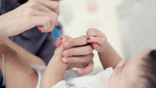 Loving Care, Closeup of Mother's Hand Expertly Cutting and Filing Baby's Nails, Ensuring Hygiene and Health - 4K Footage. photo