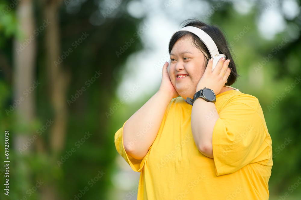 Asian girl with Down syndrome wearing headphones Smile and be happy by walking to burn fat and running slowly to exercise in a park in the middle of nature. Asian girl with Down syndrome wearing headphones Smile and be happy by walking to burn fat and running slowly to exercise in a park in the middle of nature.