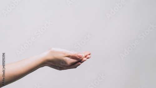 Offer hand. Take it gesture. Charity care. Woman holding copyspace in open palms proposing product isolated on gray empty space background.