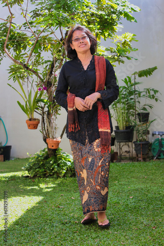 Asian woman wearing traditional Javanese clothing called Kebaya  walking in the garden