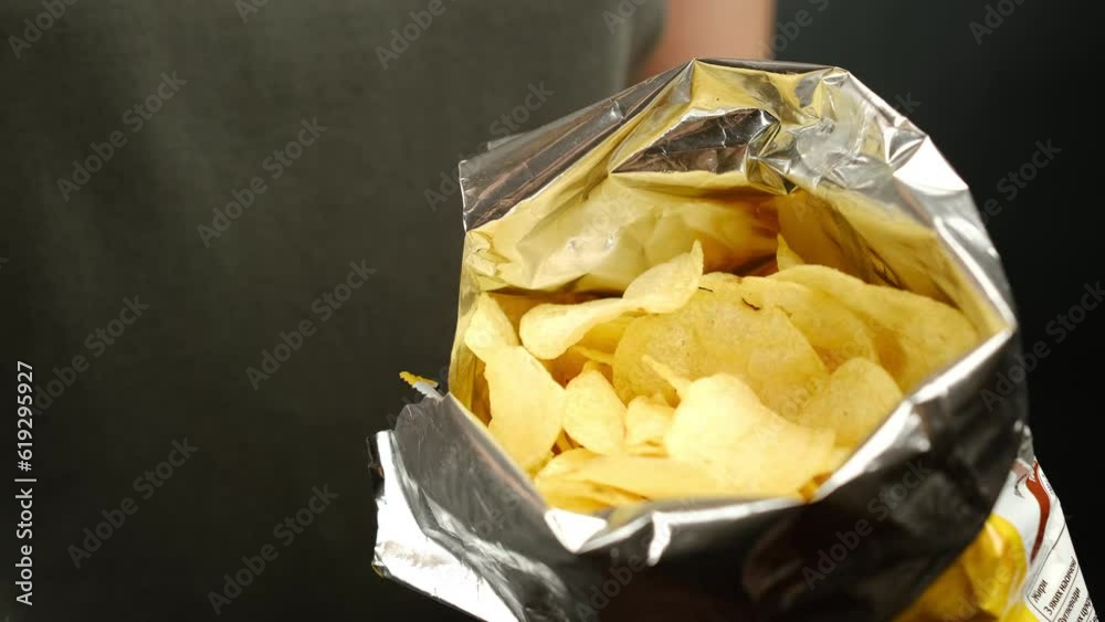 Female eating potato chips with hands from package. Unhealthy food