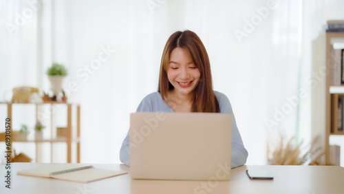 Young asian woman working at home. Happy female using computer laptop on desk at house © Monster Ztudio