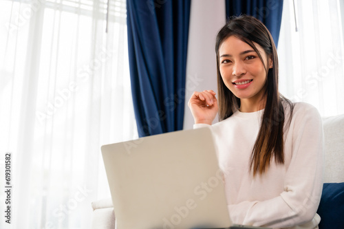 Wallpaper Mural Young asian woman using laptop while seated on couch at home Torontodigital.ca