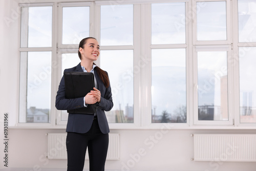 Happy real estate agent with leather portfolio in new apartment