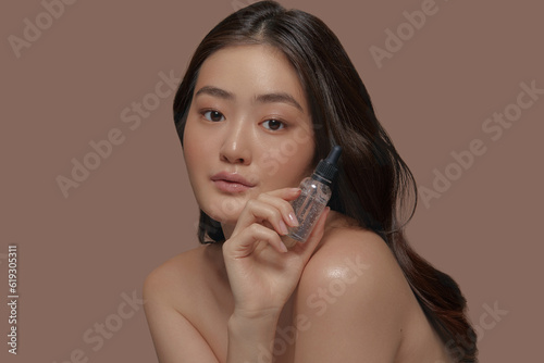 Fotografie Charming asian ethnicity young model with a fresh smooth skin holding face moist