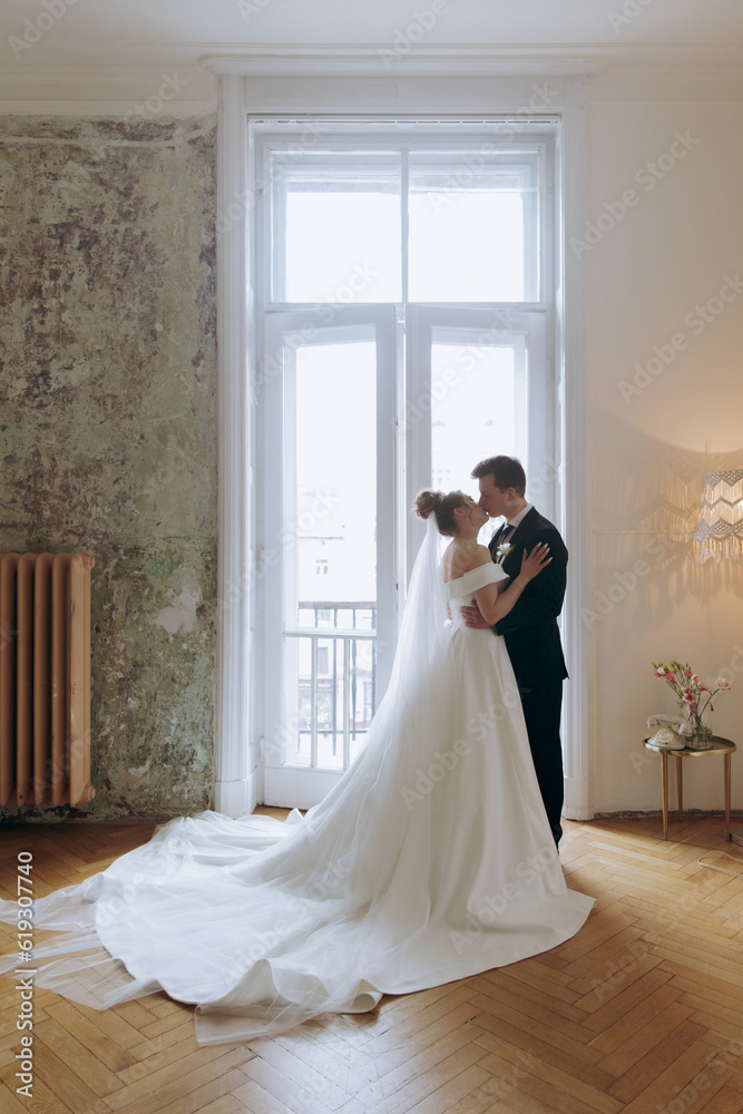 The first meeting of the groom in a black suit and the bride in a white wedding dress with a bouquet in the interior of a photo studio on a white and black background The first meeting of the groom in a black suit and the bride in a white wedding dress with a bouquet in the interior of a photo studio on a white and black background