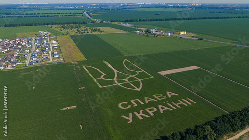 Trident - coat of arms of Ukraine on a corn field. Inscription I love Ukraine. Aerial drone view.