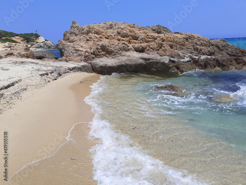 Castiadas, Italy - june 30, 2023: Punta di Santa Giusta beach, Costa Rei, in the province of the South Sardinia. A lot of soft sand between the rocks, an intense blue sea with very few bathers photo