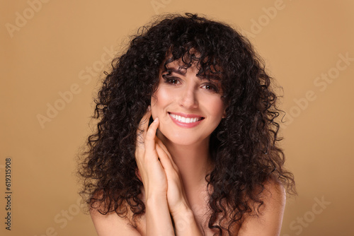 Obraz na plátne Beautiful young woman with long curly hair on beige background