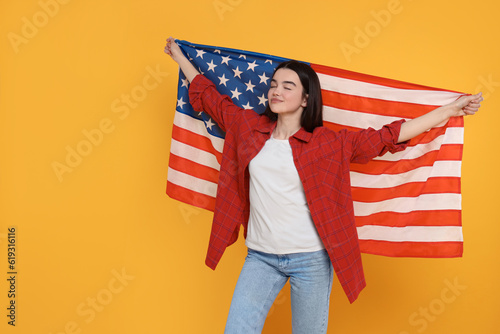 4th of July - Independence Day of USA. Happy girl with American flag on yellow background, space for text