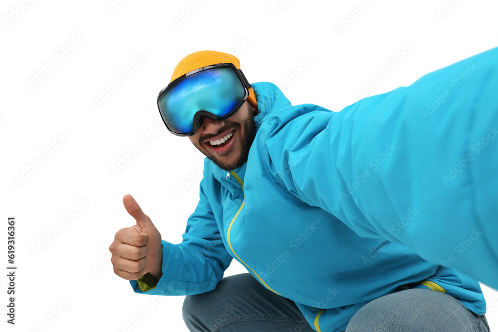 Smiling young man in ski goggles taking selfie and showing thumbs up on white background Smiling young man in ski goggles taking selfie and showing thumbs up on white background