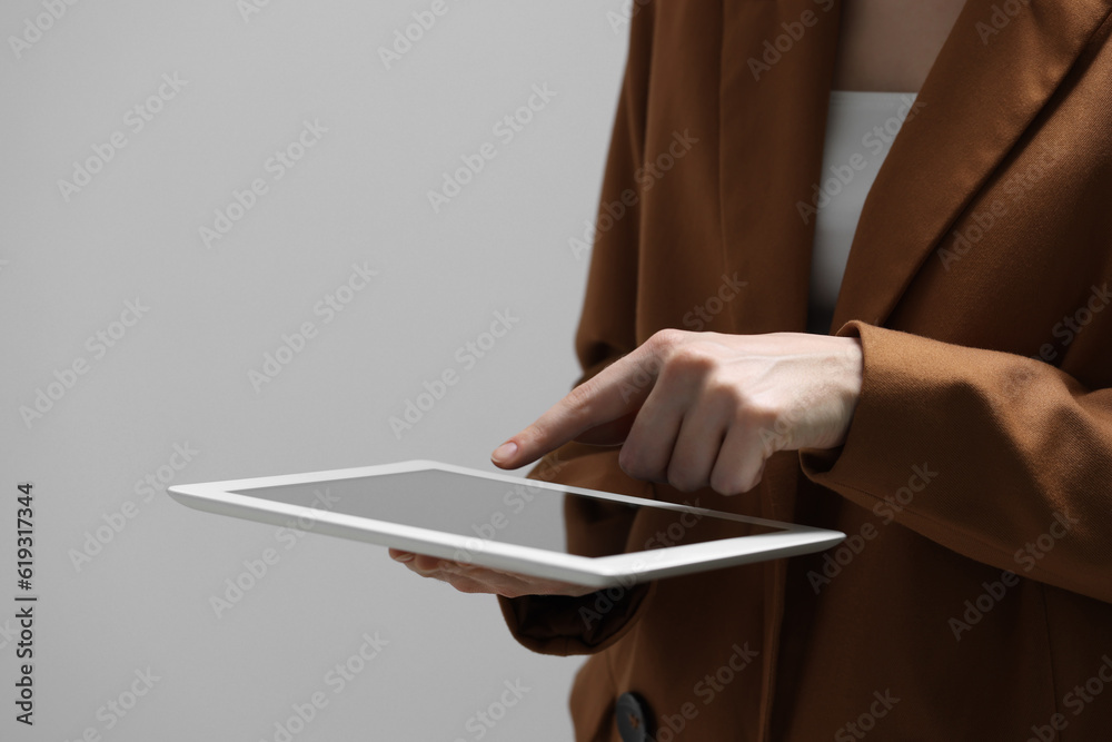 Naklejka premium Closeup view of woman using modern tablet on grey background