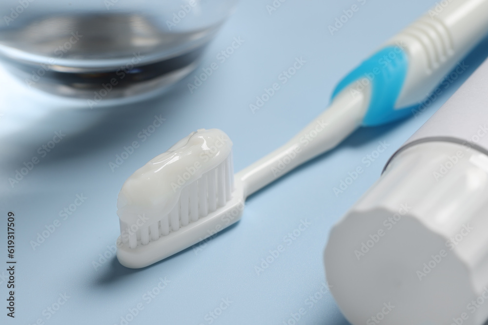 Plastic toothbrush with paste and tube on light background, closeup Plastic toothbrush with paste and tube on light background, closeup