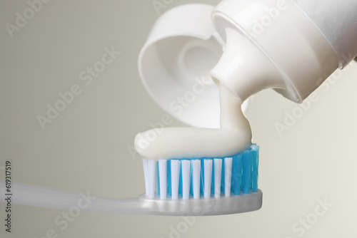 Applying paste on toothbrush against light background, closeup