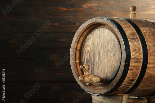 One wooden barrel with tap near wall, closeup. Space for text