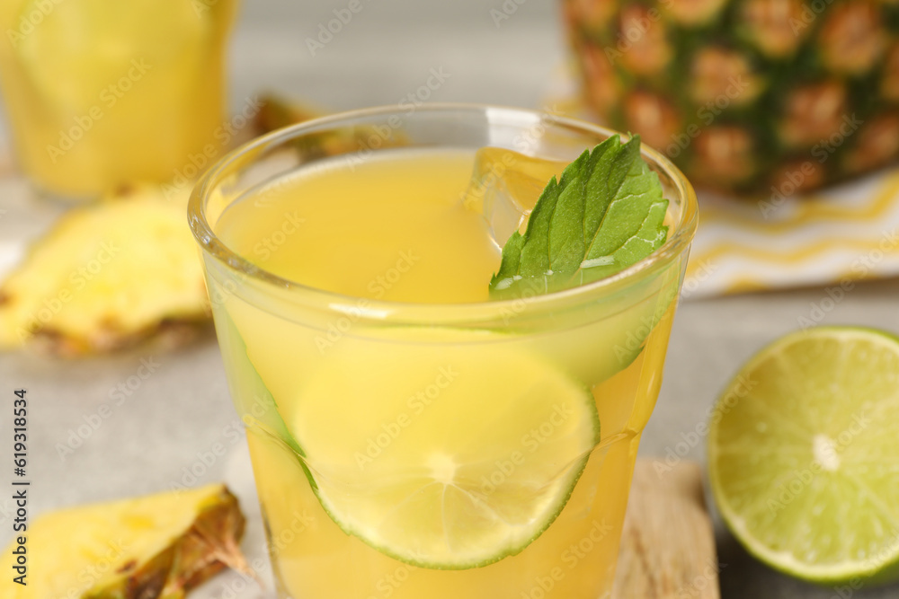 Glass of tasty pineapple cocktail with mint and lime on table, closeup Glass of tasty pineapple cocktail with mint and lime on table, closeup