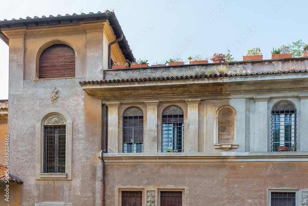Old shabby plaster facade with a window renaissance ornament and metal bars