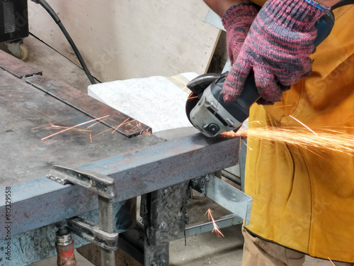 Metal processing with angle grinder. Man cutting mild steel angle bars.