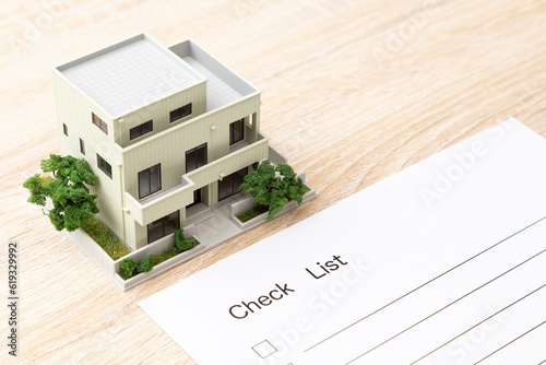 机に置かれた住宅模型とチェックリスト