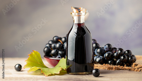 Glass bottle of organic black grape balsamic vinegar made from fermented fresh grapes. Healthy organic food black fruit, selective focus photo
