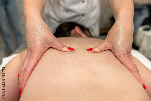 relaxed caucasian lady lying on bad and receiving a massage in a spa salon