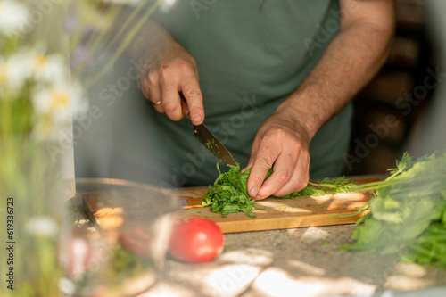 Man chopping green leafy vegetables at home photo