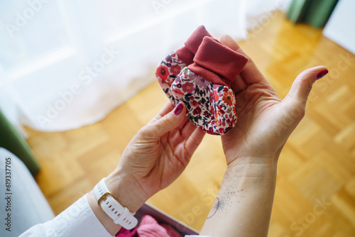 Hands of woman holding baby booties at home photo