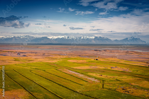 Aerial summer view of Iceland countryside with snowy mountain range on background. Green pasture on southeastern Icelandic coast. Beauty of countryside concept background.