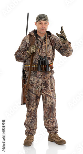 Full length portrait of happy duck hunter with a rifle and binoculars raising fore finger up and saing something important, isolated on white. Fifty-year-old man in hunting uniform posing in studio.